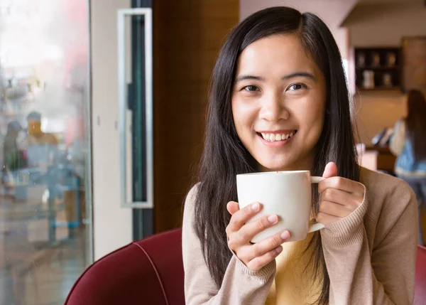 Asian woman drinking coffee in coffee shop