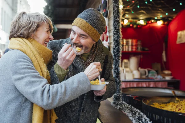 Bejaarde echtpaar eten op kerstmarkt — Stockfoto