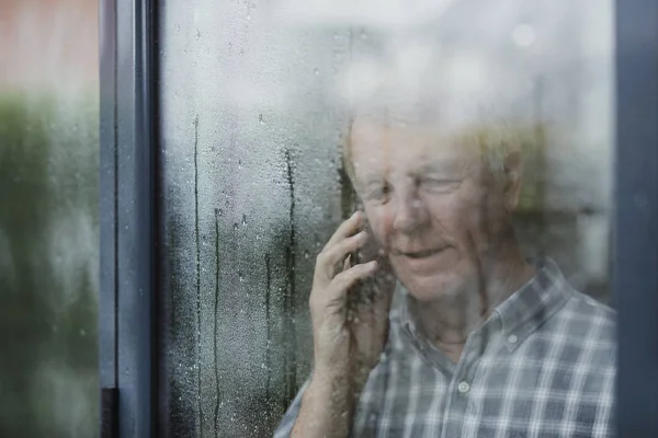 Seniorin telefoniert am Fenster — Stockfoto