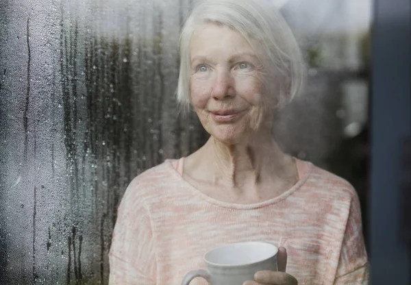 Senior kvinde nyder regnen Stock-billede