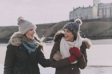 Arkadaşlar bir kış sahilde gülüyor