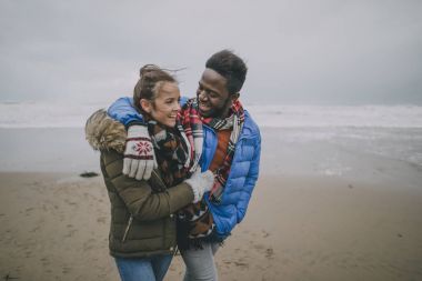 Young Couple Walk Along Winter Beach clipart