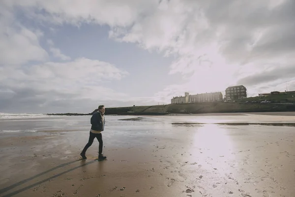 Homem jovem caminhando ao longo da praia de inverno — Fotografia de Stock