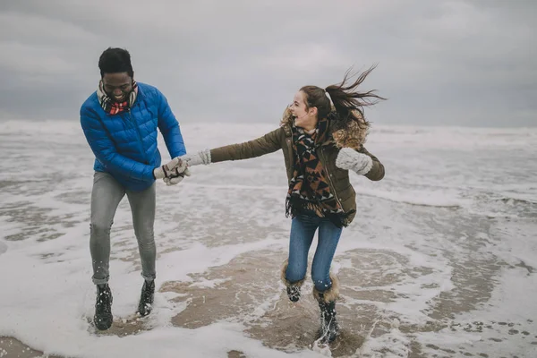 Молодая пара, смеющаяся в зимнем море — стоковое фото