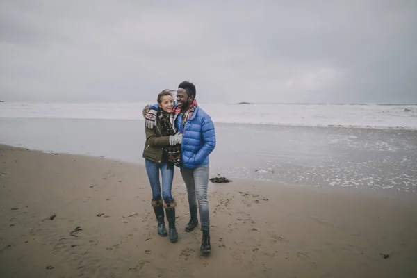 Giovane coppia fare una passeggiata romantica su una spiaggia invernale Foto Stock