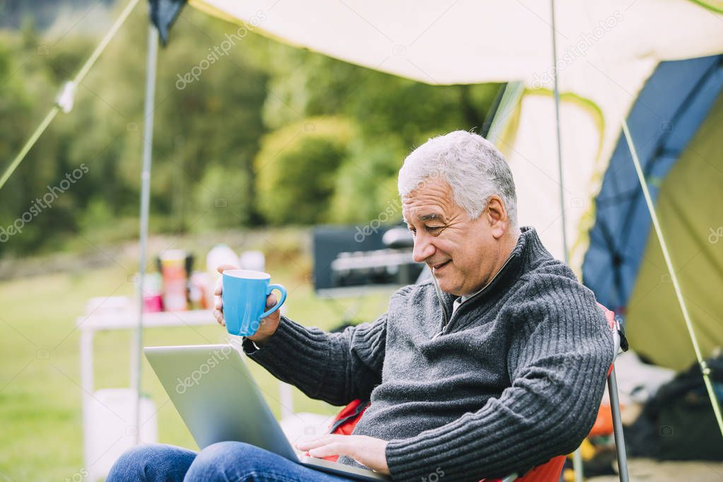 Senior man Using Laptop at Campsite