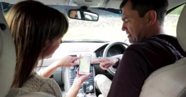 Olgun çift bir akıllı telefon onların tatil için yönergeleri alma arabalarında oturan. 