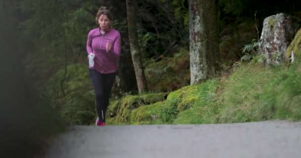 Senior Vrouw Draait Alleen Langs Een Weg Bossen — Stockvideo