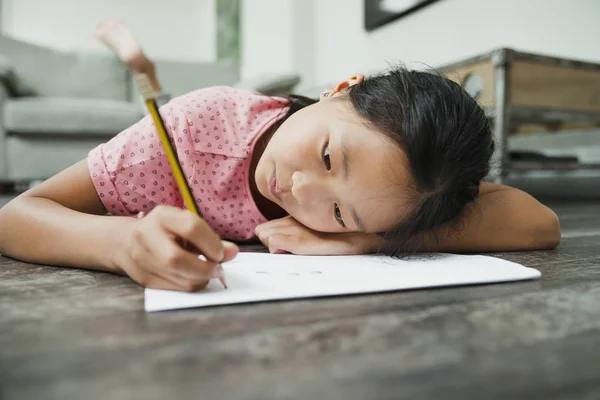 Klein meisje haar huiswerk op de verdieping — Stockfoto