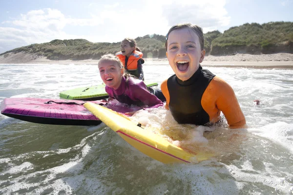 Tiga Gadis Tersenyum Untuk Kamera Saat Mereka Bodyboard Laut Bersama — Stok Foto