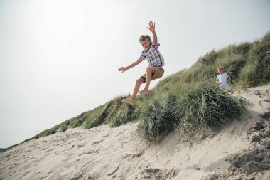 Küçük çocuk bir kumul atlama