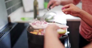 Aile Yemek stir fry birlikte evde. Hob üzerinde kızarmış tavuk için sebze eklemekte olduğunuz.