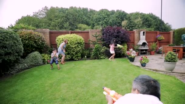 四的家庭在花园里用水手枪打架 — 图库视频影像