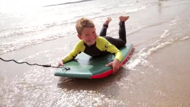 男の子に沿ってボディー ボードに引っ張られてビーチで楽しんで — ストック動画