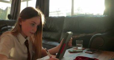 Eğer kız oturma odasında ödev yapıyor onu eve. O bir kitap, eğitim için bir dijital tablet kullanarak yazma. 