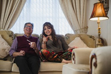 Olgun çift evde rahatlatıcı, oturma odasında televizyon izlerken. 