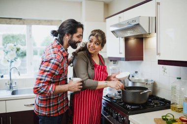 Olgun kadın mutfağında yemek ve oğlu ne yapıyor görmek için onun omuz üzerinden arıyor. 