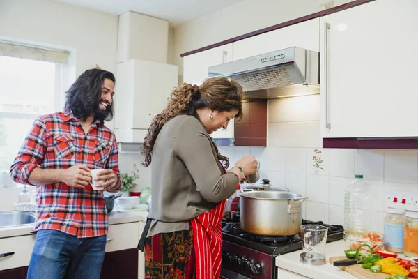 半ば成人男性は彼女が炊飯器でカレーを準備している間に 母親に話してキッチンでリラックスです — ストック写真