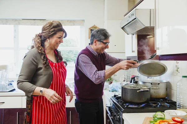 成熟したカップルは 自宅のキッチンで一緒にカレーを料理が 男は脱ぐ鍋蓋中です笑い — ストック写真