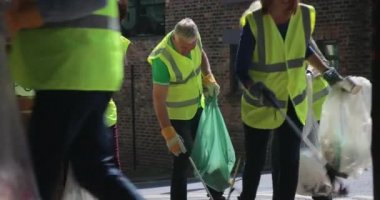 Bir grup yetişkin, çöp toplarken sokakları temizliyor..