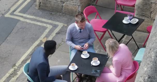 在一个城市 两个商人和一个女商人坐在户外餐桌边 一边喝酒一边谈论工作 一边看手机 — 图库视频影像