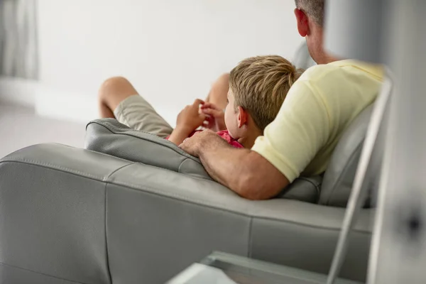 Uma Visão Traseira Menino Deitado Sofá Assistindo Com Seu Pai — Fotografia de Stock