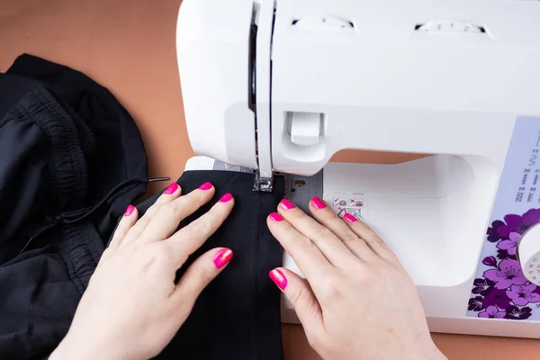 the process of tailoring, woman\'s hands with a cloth on the sewing machine