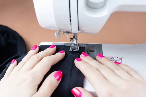 the process of tailoring, woman's hands with a cloth on the sewing machine