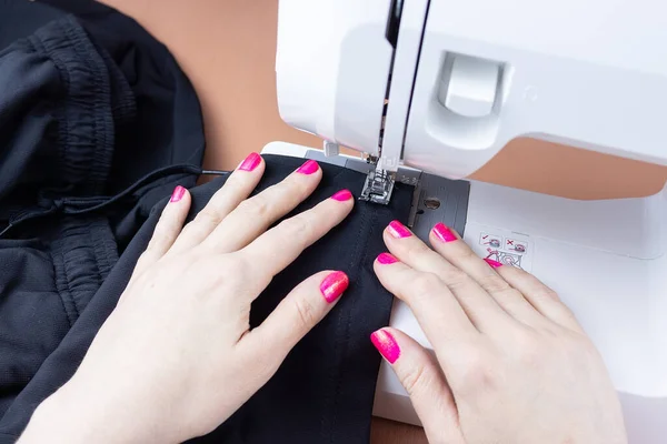 the process of tailoring, woman\'s hands with a cloth on the sewing machine