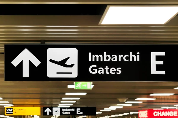 Señal de dirección de flecha en el aeropuerto que indica Imbarchi (puertas de traducción ) — Foto de Stock