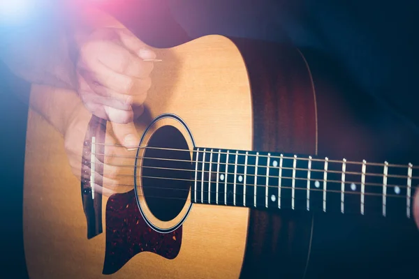 Musician's hand is strumming a yellow acoustic guitar