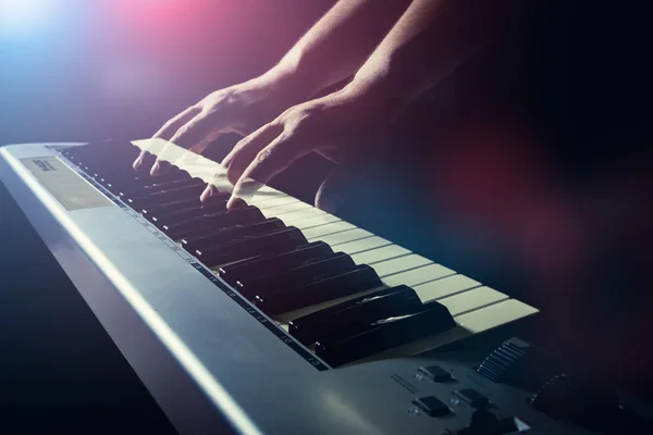 Musician\'s hand is playing a keyboard