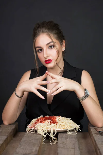 Женщина ест спагетти за деревянным столом — стоковое фото