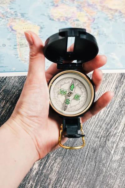 Compass in woman\'s hand on map background