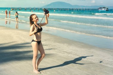 Genç bir kadın akıllı telefonuyla selfie çekiyor.