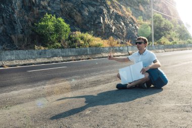 Yolda oturan genç adam otostopçu