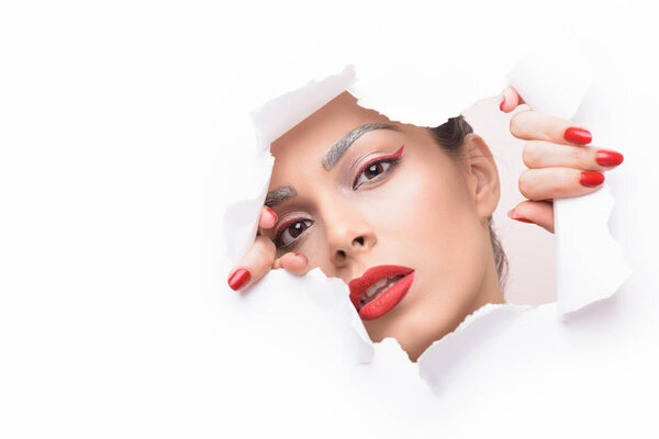 Beautiful woman looking through ripped paper.
