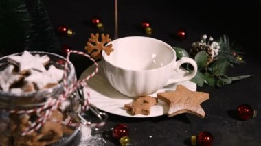 Koyu arkaplanda yıldız şeklinde zencefilli kurabiye ve ev yapımı sıcak kakao içeceği.