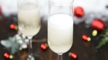 Noel ve Yeni Yıl kutlamaları donmuş şampanya kadehleriyle yapılır. Kar, kırmızı mücevherler ve köknar ağacı dallarıyla süslenmiş tatil masası.