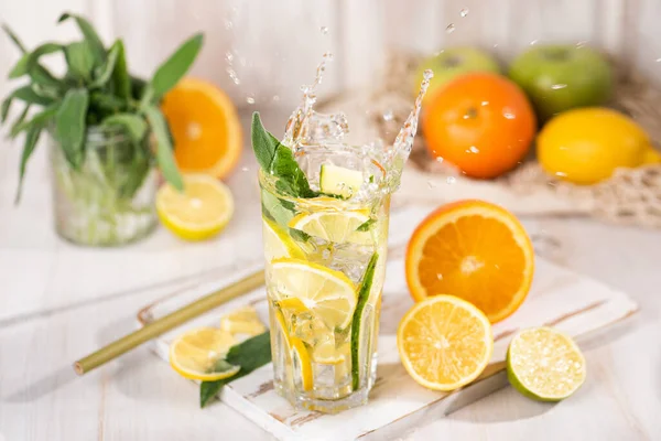 Bir bardak taze limonata ve bir damla sıvı su. Limonlu, adaçaylı, portakallı ve ahşap kaplama buzlu içecek. Soğuk yaz içeceği ya da kokteyl