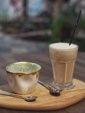 İki fincan kahve. Kahve masasında beyaz ve altın seramik kahve, altın latte sanat eseri ve bir bardak kapuçino.