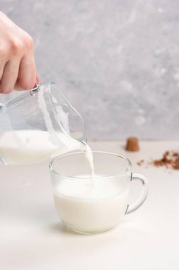 Beyaz bir masanın üzerine cam bardağa süt dökmek. Süt şişesinde çiftlikten alınmış inek sütü. Gri mermer arkaplan