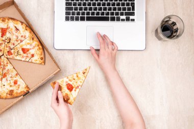 Karton kutuda pizza ve hafif mermer arka planda dizüstü bilgisayar. Metnin için alanı kopyala. Üst manzara, düz yatış. Paket yemek konsepti