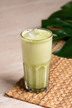 Hindistan cevizi sütlü ve mermer kaplama beyaz çikolatalı bir bardak matcha latte. Tropik canavar yaprağı.