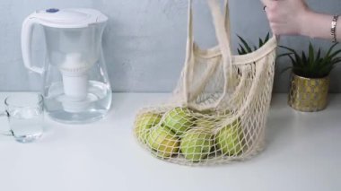 Kadın eli, alışveriş çantasından meyve çıkarır. Sıfır atık ve geri dönüşüm konsepti. Plastik sağlıklı hayat yok..