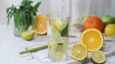 Buz küplü bir bardağa limonata dökmek. Meyve suyu, tahta bir masada yaz içeceği.