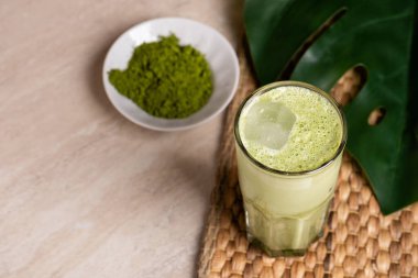 Hindistan cevizi sütlü ve mermer kaplama beyaz çikolatalı bir bardak matcha latte. Tropik canavar yaprağı.