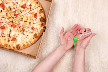 Karton kutuda pizza ve açık mermer arka planda el dezenfektanı. Metnin için alanı kopyala. Üst manzara, düz yatış. Paket yemek konsepti