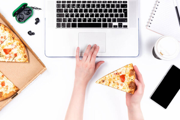 Pizza in a cardboard box and laptop on a white background. Copy space for your text. Top view, flat lay. Takeaway food concept