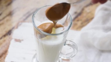 Buzlu Dalgona kahvesi ve ahşap tepside kremalı hazır kahve. Mermer kahverengi masada Kore içkisi lattesi